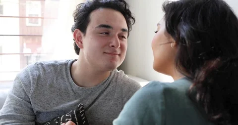 Close-up handheld shot of young couple sitting on sofa and talking face to face Stock Footage 120428508