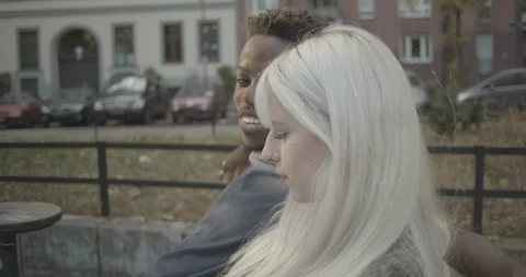 Close-up handheld shot of young couple talking while sitting on park bench Stock Footage 120433149