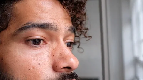 Close-up handheld shot of young curly haired man with beard looking away Video stock 120433697