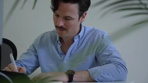 Close-up handheld shot of young man smiling while making notes in planner Stock-Footage 114872932