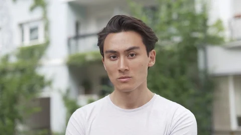 Close-up handheld shot of young man posing for camera on city street Stock Footage 114875923