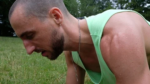 Close-up handheld shot of young man doing plank during exercising in park Video stock 120432127