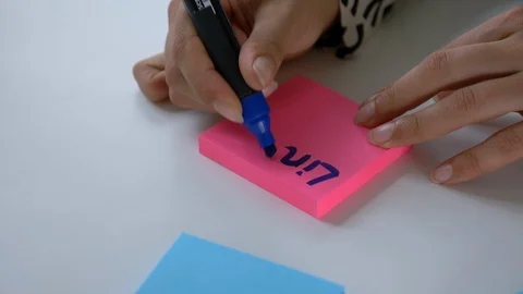 Close-up handheld of woman's hand writing on a sticky note in office 스톡 동영상 114871384