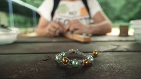 Close-up of a handmade bracelet made of beads on a blurred background of a woman Stock Footage 119647213