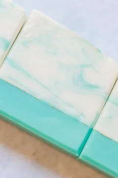 Close-up of handmade soap bars with teal and white marbled design 写真素材