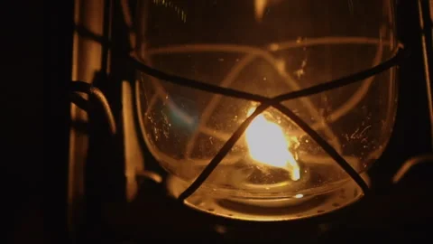 Close-up hands adjust orange flame on kerosene oil lamp on dark night Stock Footage 259741872