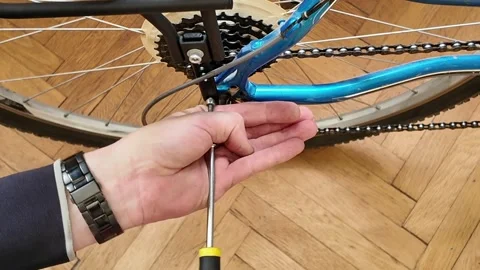 Close-up of hands adjusting bicycle rear rack with screwdriver on wooden floor. Stock Footage 337967555