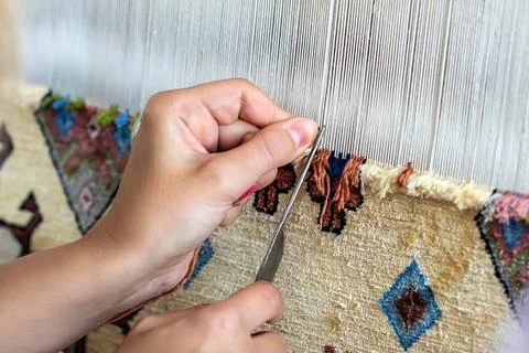 Close-up of hands adjusting fine threads on a traditional handloom during fab Foto stock