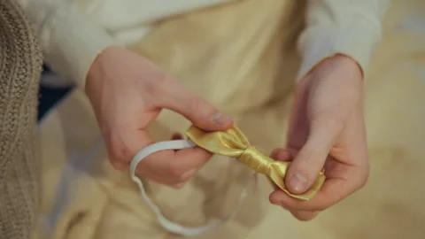 Close up hands adjusting small golden shiny bow tie on elastic band against Stock Footage 346732399