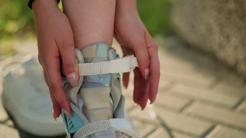 Close-Up of Hands Adjusting Strap on Roller Skating Shoe Under Sunlight Stock Footage 289094893