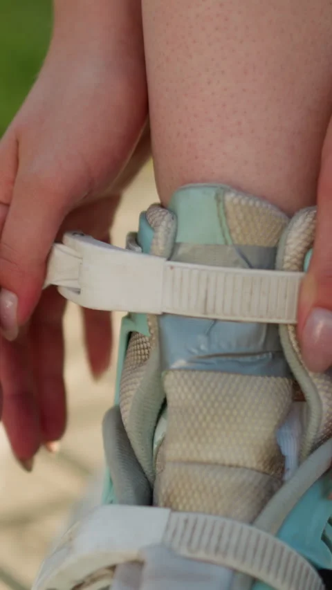 Close-Up of Hands Adjusting Strap on Roller Skating Shoe Under Sunlight Stock Footage 310521222