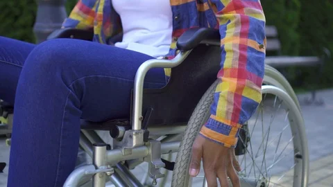 Close up of the hands of african disabled young woman in a wheelchair in Park Video stock 111151060
