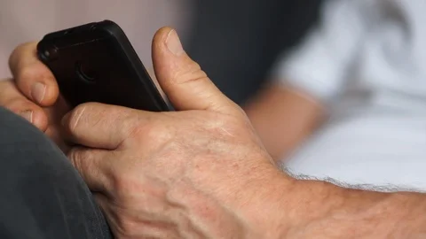 Close-up, hands and face of an elderly man working with his smartphone while Video stock 121274565