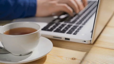 Close up on hands of anonymous man working on laptop with cup of hot tea, focus Video stock 105633419