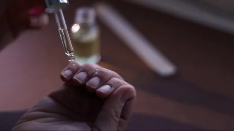 Close-up of hands applying cuticle oil with a dropper, a drop falling onto .. Stock Footage 333845734