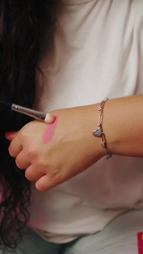 A close-up of hands applying makeup product onto a forearm with a soft brush. Stock Footage 327463790