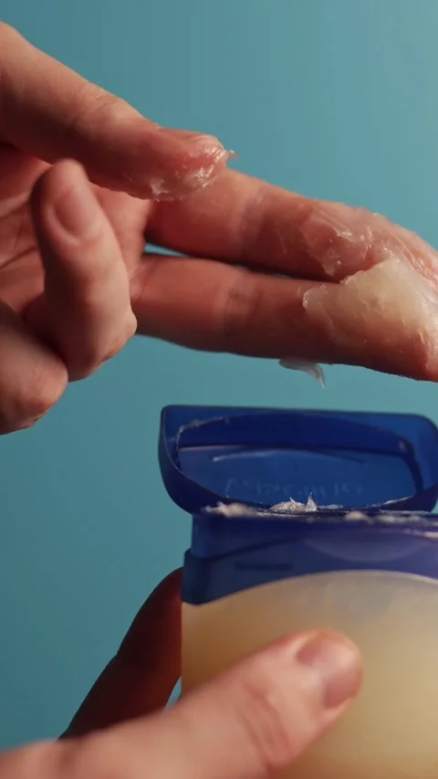 Close-up of hands applying petroleum jelly for skin care and healing Stockbeeldmateriaal 343838038
