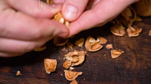 Close-up hands are cleaning a walnut from the shell. Stock Footage 249053878