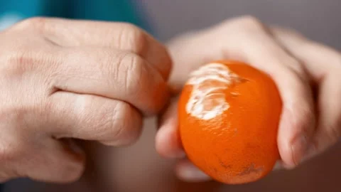 Close-up hands are peeling orange and tasty tangerine. Stock Footage 165585069