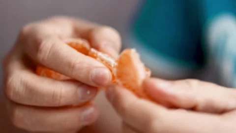 Close-up hands are peeling orange and tasty tangerine. Stock Footage 165674643