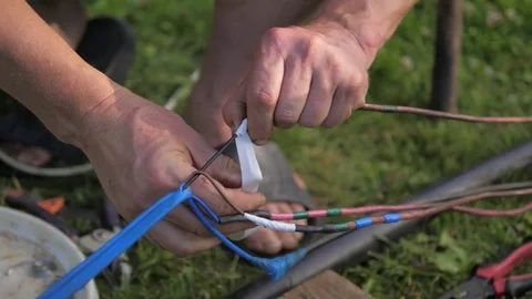 Close-up, the hands are wound with electric wires from the tape. Video stock 77534538