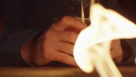 Close Up of Hands Around a Pint of Beer in front of Warm Fire 動画素材 83360579