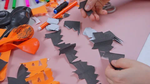 Close up of hands arranging cut black paper bats into rows on a pink work s.. Stock Footage 346800430