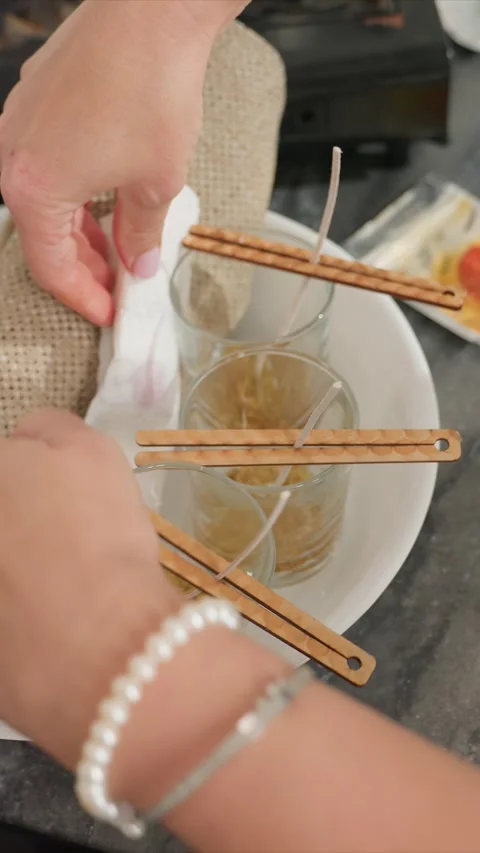 Close up of hands arranging wood wick holders over candles on marble countertop Stock Footage 344682150