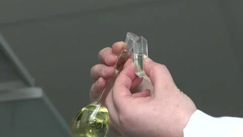 Close-up of hands of assistant pouring yellow liquid into flask Video stock 126748017