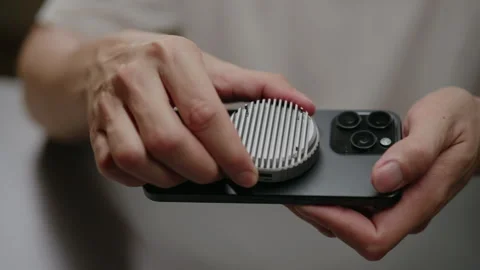 Close-up of hands attaching circular cooling fan to mobile phone. Person using Stock Footage 348085256