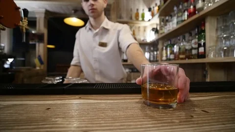 Close-up, hands the bartender poured and served whiskey at the bar Stock Footage 85173675