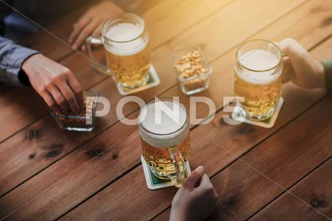 Close up of hands with beer mugs at bar or pub Stock Photos
