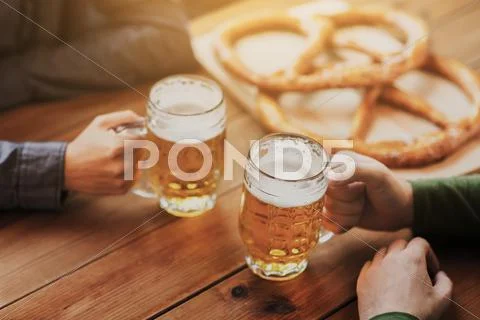 Close up of hands with beer mugs at bar or pub Stock Photos