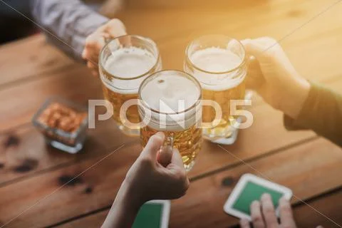 Close up of hands with beer mugs at bar or pub Stock Photos