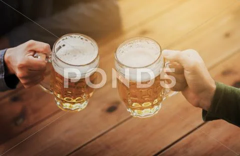 Close up of hands with beer mugs at bar or pub Stock Photos