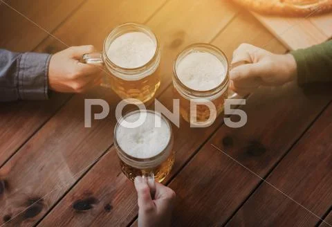 Close up of hands with beer mugs at bar or pub Stock Photos