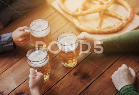 Close up of hands with beer mugs at bar or pub Stock Photos