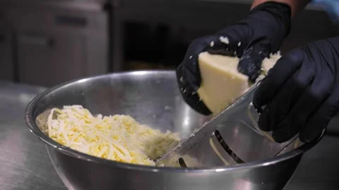 Close-up of hands in black gloves grating cheese on coarse grater in kitchen. Stock Footage 267671245
