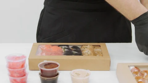 Close-up hands in black gloves pack sushi 動画素材 129876344