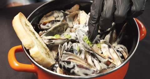 Close-up of hands in black gloves putting mussels in cream sauce on toast Stock Footage 134038582