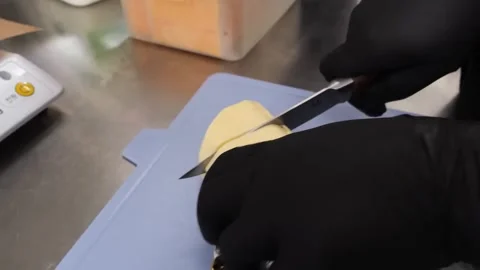 Close-up of hands in black gloves slicing a block of butter on a blue cutting bo Stock Footage 331632707