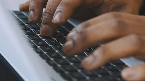 Close up, hands of a black man typing on the laptop keyboard. remote work concet Stock Photos