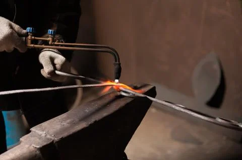 Close-up - Hands Of A Blacksmith Weld Elements To Their Forged Product Foto stock