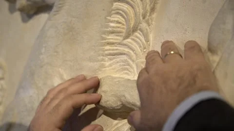 Close up of the hands of a blind man touching the head of a statue at the Ta Stock Footage 140610320