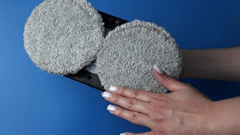 Close-up of hands on a blue background showing a robot window cleaner with the Stock Footage 307170033