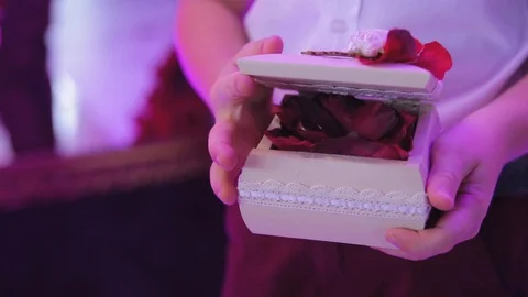 Close-up hands of boy open box in which lying gold ring on petals of roses Stock Footage 100686509