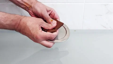 Close-Up of Hands Breaking a Chocolate Bar into Pieces on Table Surface Stock Footage 315493512