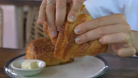 Close up of hands breaking in half freshly baked crusty flaky buttery croissant Video stock 159801587