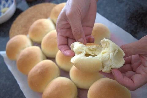 Close up of hands breaking open soft fresh homemade pandesal Stock Photos