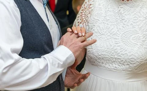 Close up of hands as bride placing wedding ring on groom finger during cere.. Фото